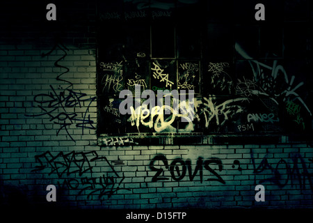 Dark Grungy alleyway with graffiti covered wall texture Stock Photo