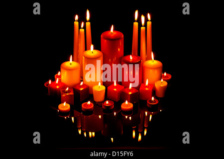 A group of red and white Christmas candles on a black reflective surface Stock Photo