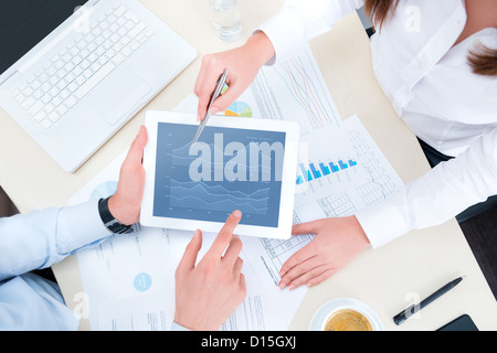 Businessman and businesswoman analyzing financial report on a modern digital tablet. Top view shot. Stock Photo