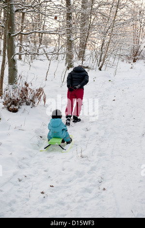 Mother pulling snow sledge up a hillside Stock Photo