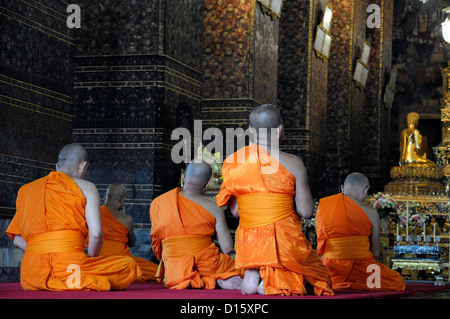 orange robed monks pray praying chant chanting Wat Pho Temple of the reclining buddha buddhist shrine temple bangokok Stock Photo