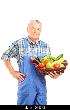 Mature farmer holding a basket full of fresh vegetables isolated against white background Stock Photo