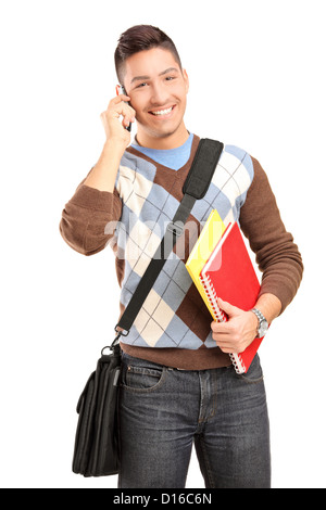 A smiling male student with shoulder bag and books talking on a cell phone isolated against white background Stock Photo