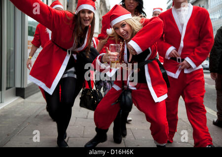 London, UK. Sunday 9th December 2012. A flash mob of Santas descends play to camera. Christmas celebrated here with the annual Santa Pub Crawl party visiting the famous pubs & sights of London with everyone decked out in jolly red Santa suits. Organised by Fanatics, an Australian sports and party company. Alamy LIve News Stock Photo