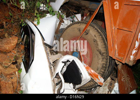 car and Lorry Accident in India.Fully crashed down car and Huge Truck tyres above the top of car Stock Photo