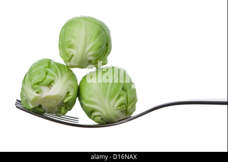 brussel sprouts three fresh on a fork against white Stock Photo