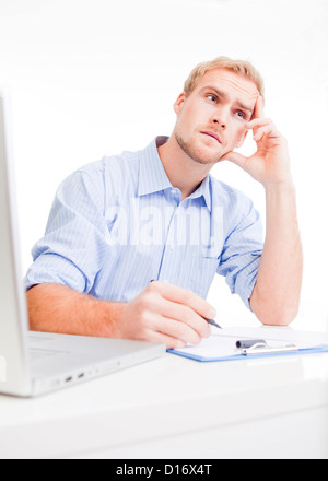 young man at desk in office thinking, contemplating Stock Photo