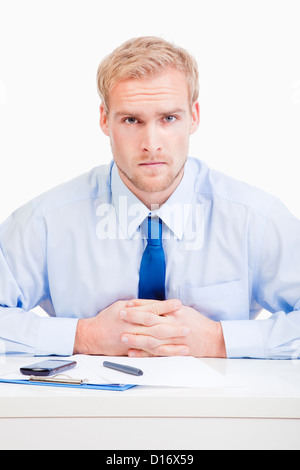 serious boss sitting behind desk at office looking at camera Stock Photo