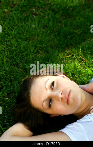 Berlin, Germany, thoughtful young woman lying in the grass Stock Photo