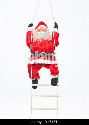 closeup of happy toy santa climbing a plastic and rope ladder isolated on white Stock Photo
