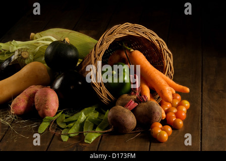 Thanksgiving cornucopia filled with autumn fruits and vegetables on wooden table. Stock Photo