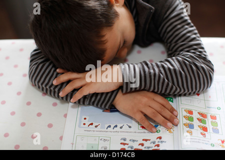 6-year-old boy falling asleep on his homework Stock Photo