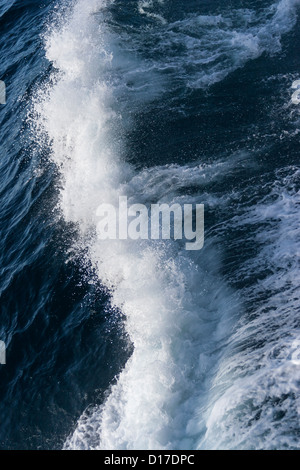 Waves breaking, wake off the side of a cargo ship in deep ocean Stock Photo
