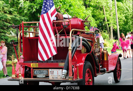 Antique firetruck adorned with American flags partaking in a small town Memorial day parade on Main Street USA. Stock Photo