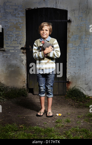 Boy holding chicken outdoors Stock Photo