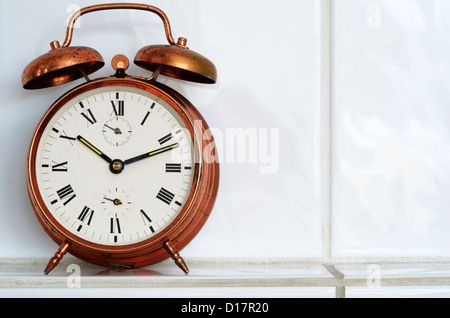 old-fashioned copper alarm clock on the mantelshelf Stock Photo