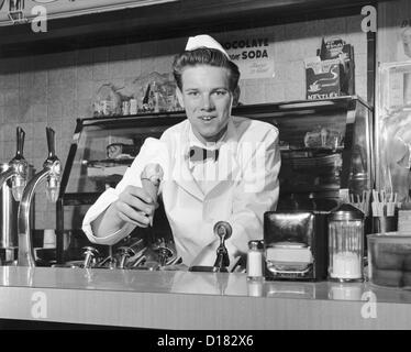 Soda jerk holding ice cream cone, 1960's Stock Photo