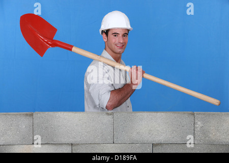 Bricklayer carrying a spade Stock Photo