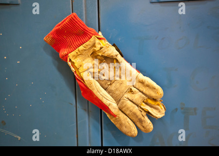 worn workman's glove against a blue painted surface Stock Photo