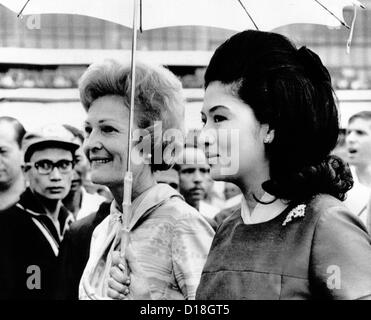 First Lady Pat Nixon (left) and Imelda Marcos stand under an umbrella at Manila airport. President Nixon conferred with Stock Photo