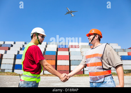 two happy workers handshaking before transportation containers Stock Photo