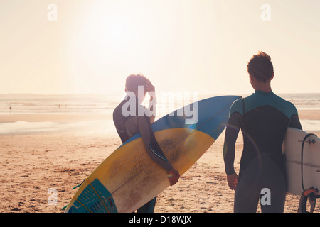 Surfers looking out towards sea Stock Photo