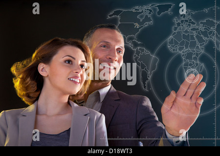 Businesspeople touching world map Stock Photo