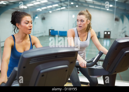 Two women working out on exercise bikes Stock Photo