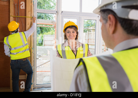 Woman smiling at architect while man is measuring Stock Photo
