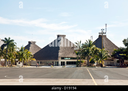 view from arriving aircraft of lush tropical palm studded setting for palapa style roofed pavilions of Bahia de Huatulco airport Stock Photo