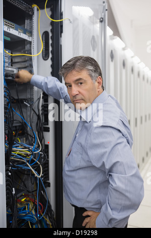 Technician looking up from adjusting server wires Stock Photo