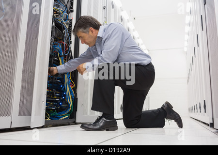 Technician kneeling and repairing a server with his hands Stock Photo