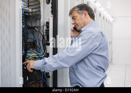 Technician phoning while repairing a server Stock Photo