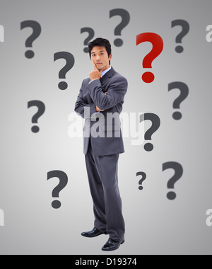 Businessman thinking surrounded by question marks Stock Photo