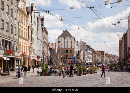 City centre street scene with overhead tram lines and people dining outside in pavement cafes in Augsburg, Bavaria, Germany Stock Photo
