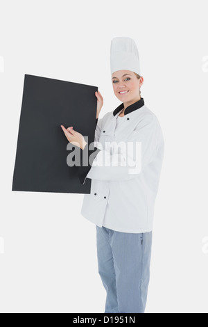 Female chef pointing on black billboard Stock Photo