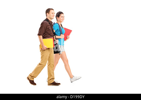 Full length portrait of a two students holding books and walking isolated on white background Stock Photo