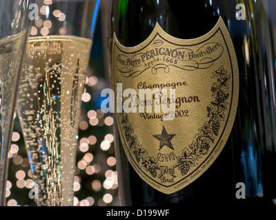 DOM PERIGNON Bottle and freshly poured glasses of 2002 Dom Perignon luxury vintage champagne with sparkling lights in background Stock Photo