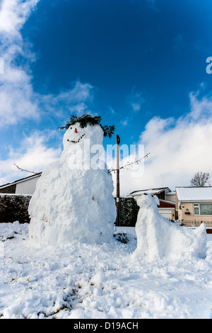 Snowman and a pet snowdog stand against a blue sky in winter Stock Photo