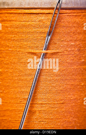 Spool of yellow thread with a needle stuck in it. Stock Photo