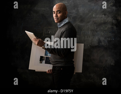Businessman by blackboard with digital tablet and moodboard Stock Photo
