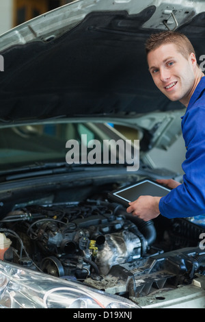 Happy mechanic holding tablet pc Stock Photo