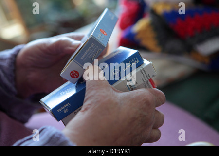 Elderly woman at in home with confusing range of different daily medications, Suffolk, UK Stock Photo