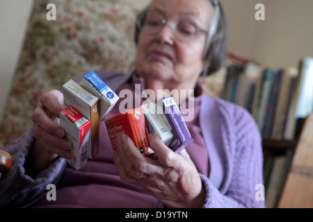 Elderly woman at in home with confusing range of different daily medications, Suffolk, UK Stock Photo