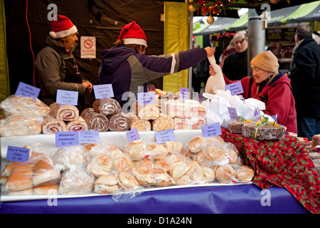 Bread and cakes for sale on Christmas market stall in winter people shopping shopper York North Yorkshire England UK United Kingdom GB Great Britain Stock Photo