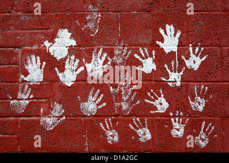 Red brick wall with hand prints in white paint, Kilmarnock, Ayrshire, Scotland Stock Photo