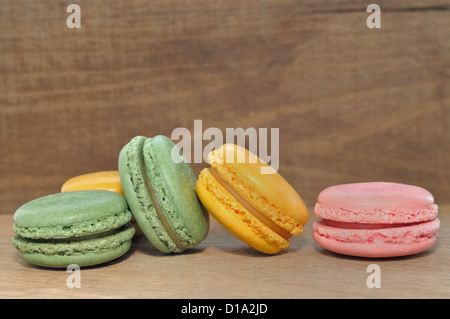 macaroons pink, green and yellow arranged on a wooden background Stock Photo