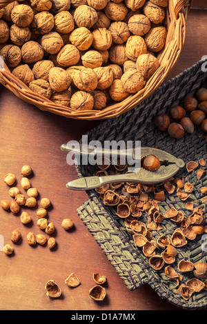 Hazelnuts and walnuts with in wicker basket on old table Stock Photo