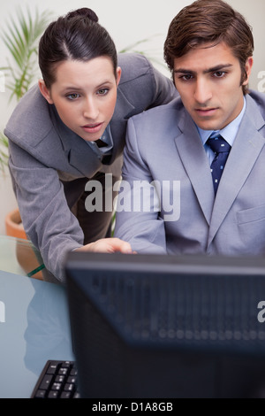 Colleagues looking at computer screen in office Stock Photo
