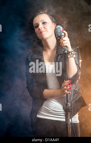 Beautiful singer with microphone on stage Stock Photo